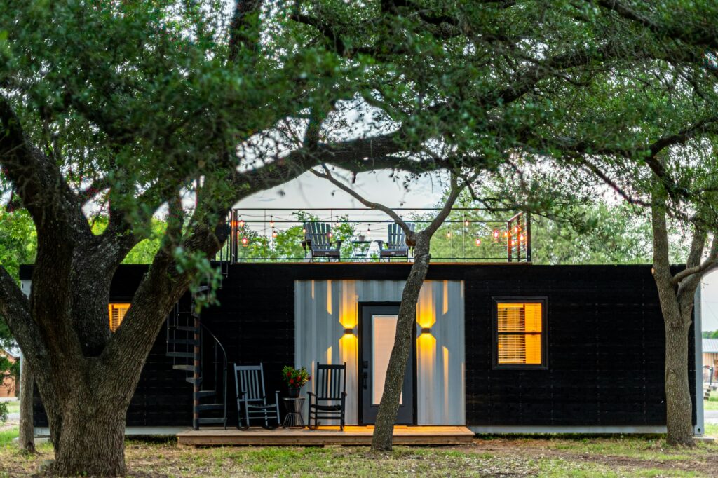 Modern Tiny House Nestled Among Trees Exterior of a tiny house surrounded by trees at sunset – tiny house news update