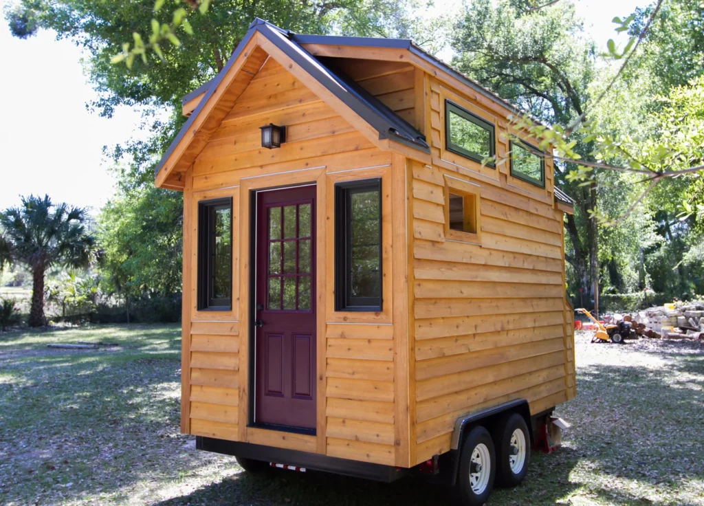 Minimalist tiny home lifestyle example featuring a compact wooden house on wheels surrounded by nature.