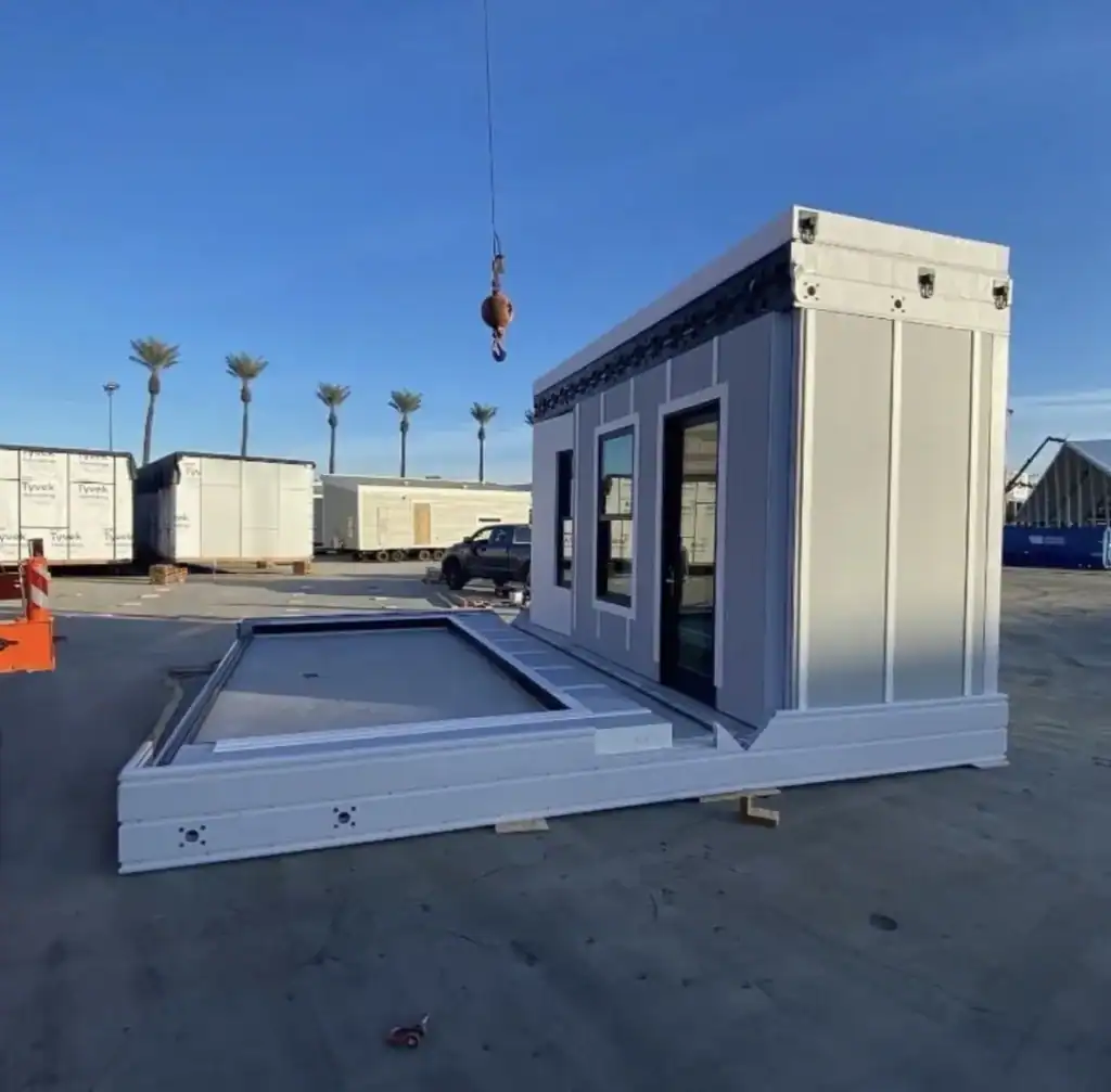 Foldable tiny home unit partially expanded at an outdoor construction facility