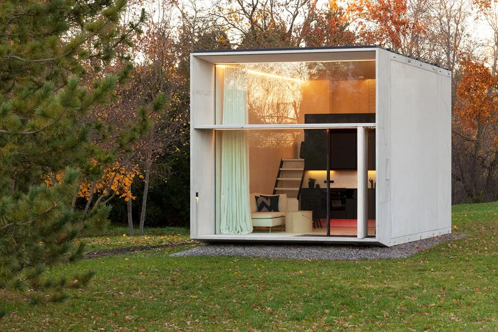 Modern eco friendly tiny house with full glass facade in an autumn forest