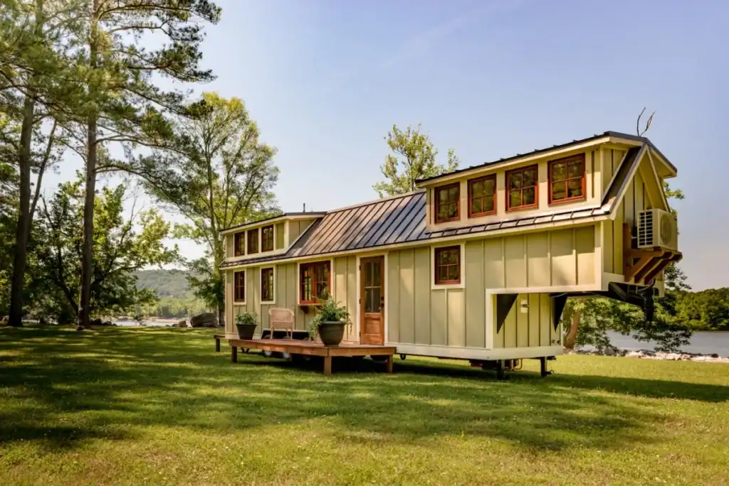 Modern tiny home with loft windows and deck, built by U.S. tiny house builders near a lake
