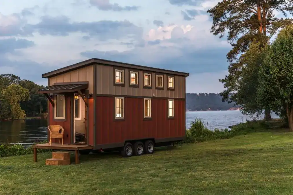 Large Mobile Tiny Home with Rustic Exterior and Deck Spacious mobile tiny home with wood siding, large windows, and a front porch by top U.S. tiny house builders