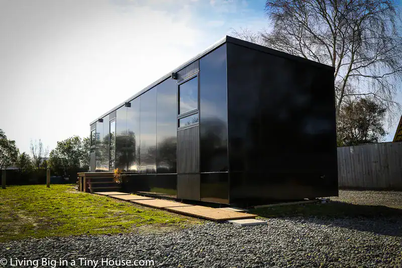 Black container-style earthquake resistant tiny home in rural setting
