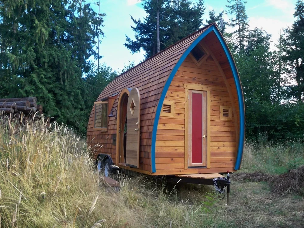 Unique arched tiny house with custom wood shingles created by a skilled tiny home builder.