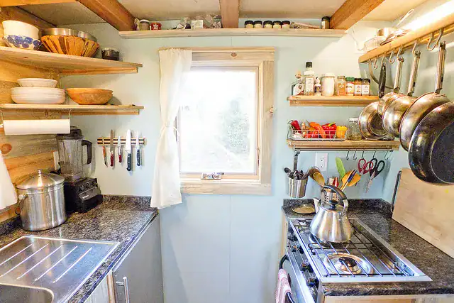 Small galley kitchen with pots, spices, and knives organized, illustrating tiny home kitchen storage ideas.