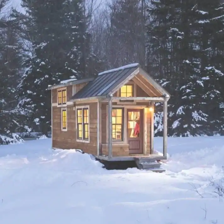 Cozy tiny home glowing at night demonstrating how to heat a tiny home in winter efficiently