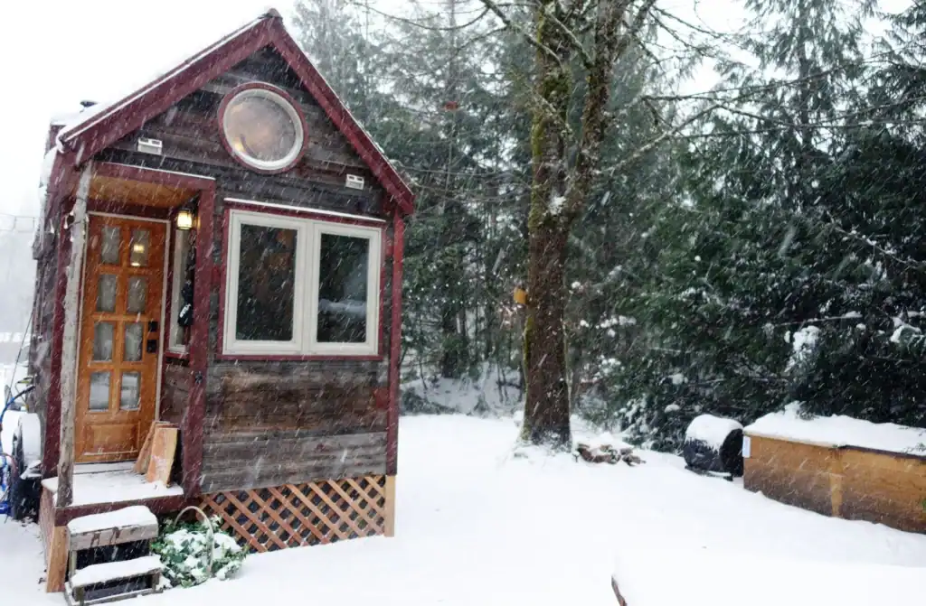 Snow-covered tiny home showing how to heat a tiny home in winter through insulation and heating systems
